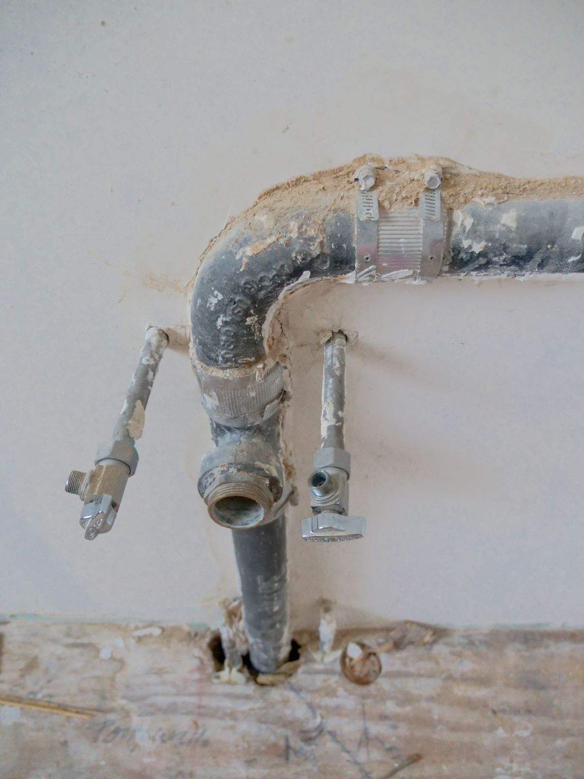Corroded old plumbing pipe in a wall before replacement