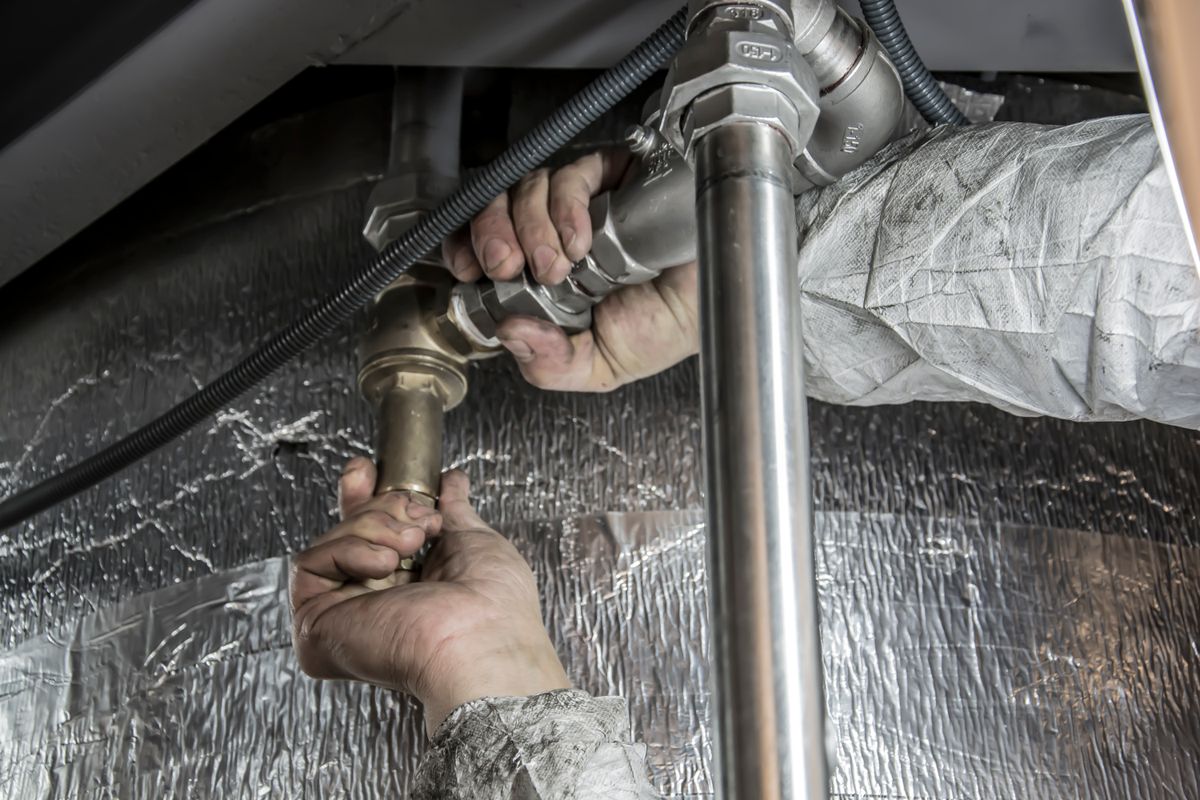 Plumber tightening a chrome trap under a sink